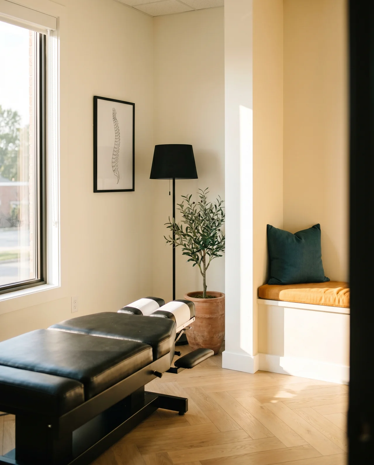 Modern Round Rock chiropractic clinic treatment room with natural light, warm ivory walls, and a sleek black adjusting table
